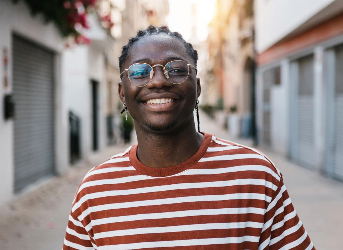 A smiling young man in glasses and a striped T-shirt